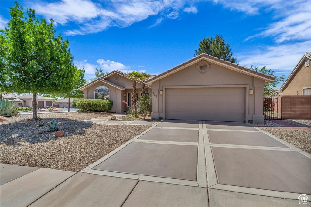 View of front of house with stucco siding, driveway, an attached garage, and a tile roof