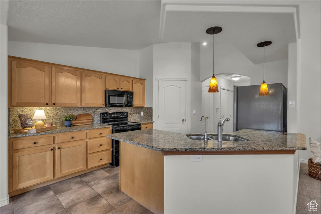 Kitchen featuring black appliances, lofted ceiling, a sink, tasteful backsplash, and dark stone countertops