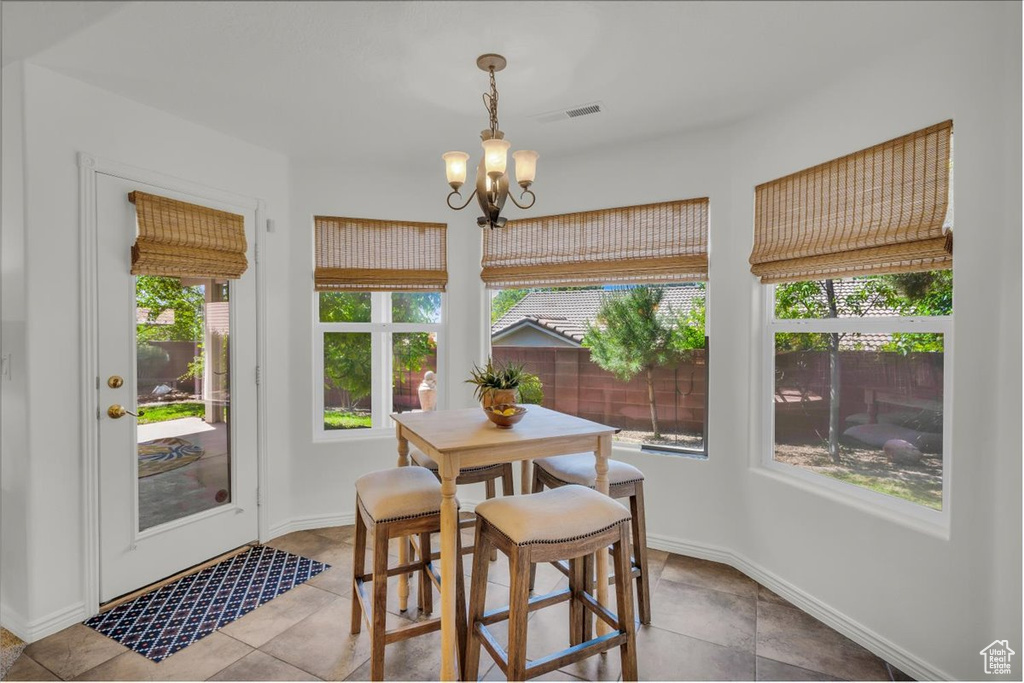 Tiled dining room with a chandelier and baseboards