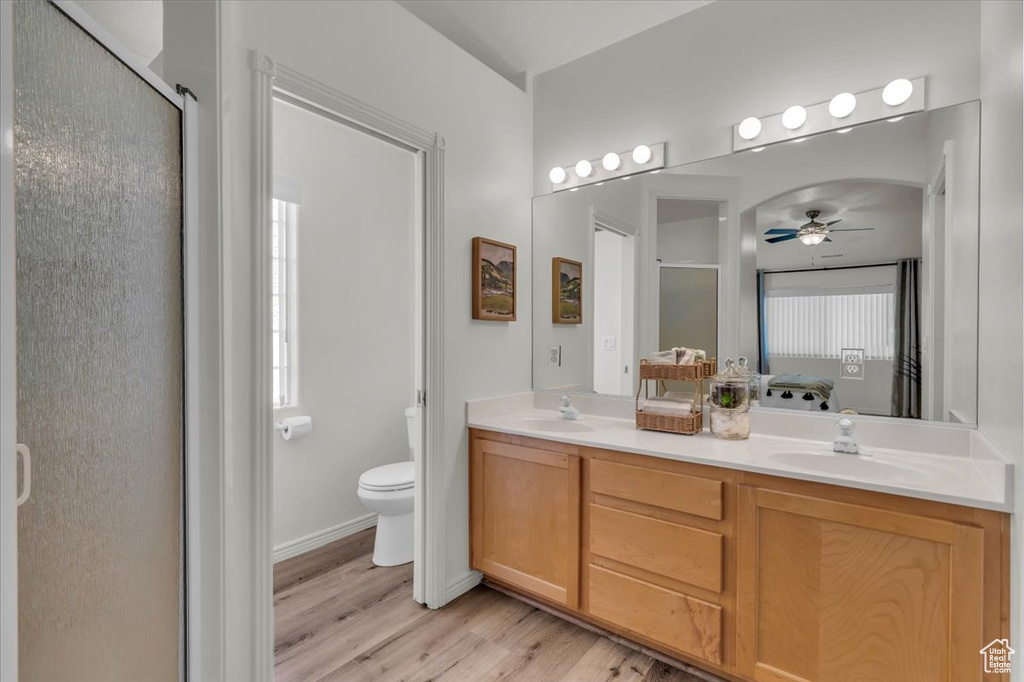 Full bathroom with ceiling fan, double vanity, wood finished floors, and a shower stall