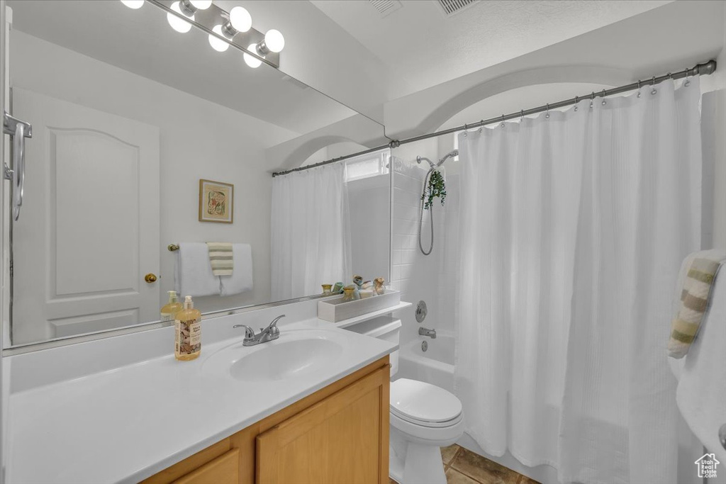 Full bathroom with vanity, toilet, shower / bathtub combination with curtain, and tile patterned floors