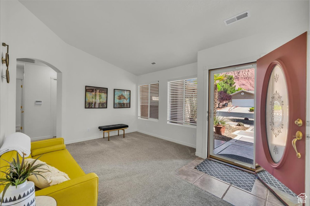 Entrance foyer with vaulted ceiling, arched walkways, carpet floors, and baseboards