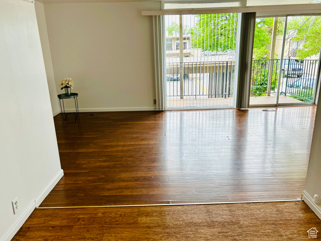 Empty room featuring plenty of natural light, wood finished floors, and baseboards