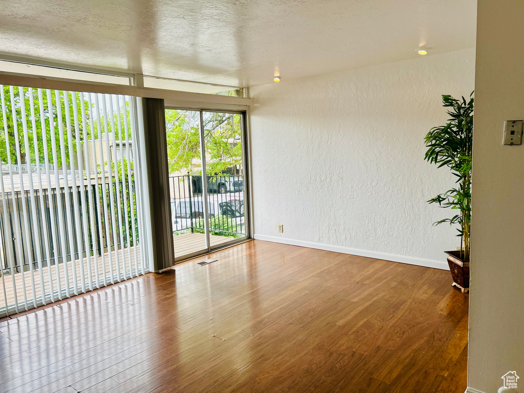 Spare room featuring a textured wall, wood finished floors, and baseboards