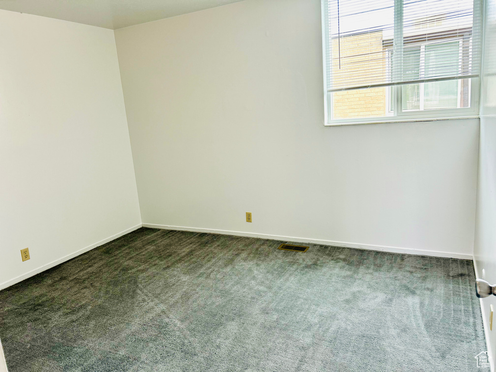 Empty room featuring dark colored carpet and baseboards