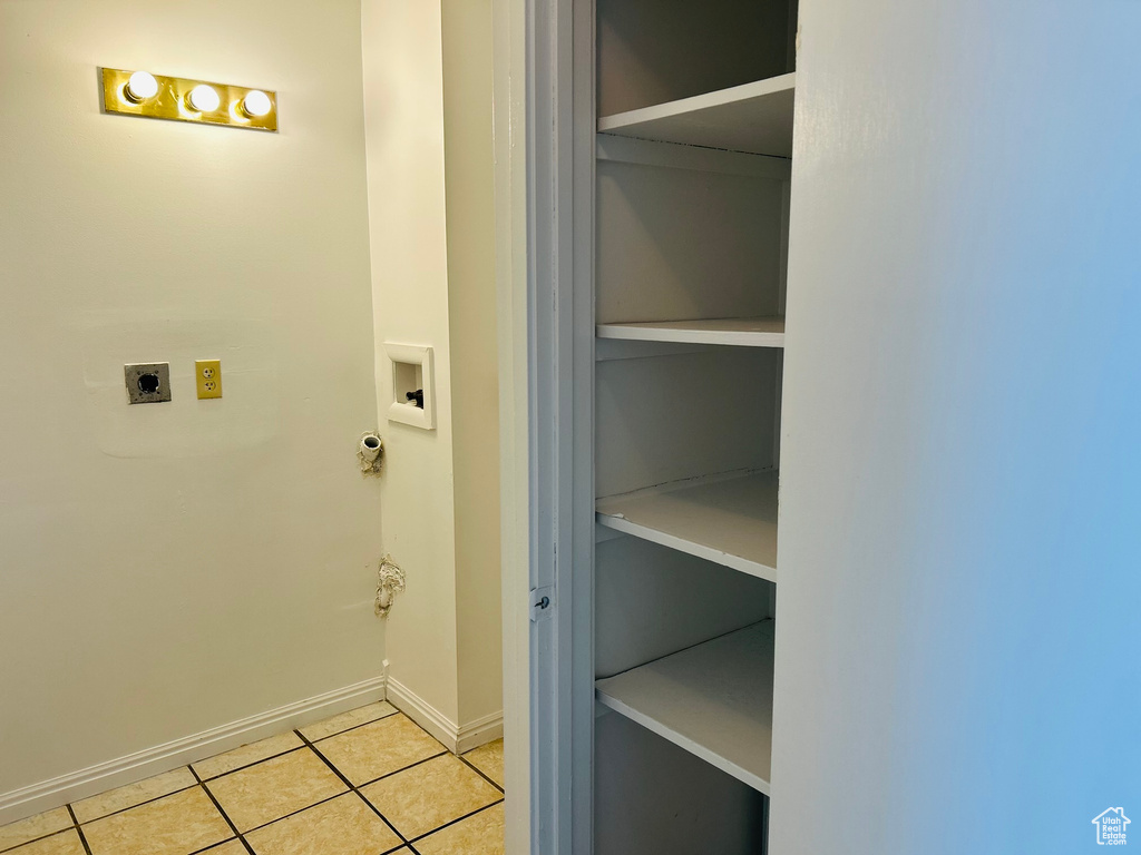 Laundry area with hookup for an electric dryer, light tile patterned floors, washer hookup, and baseboards