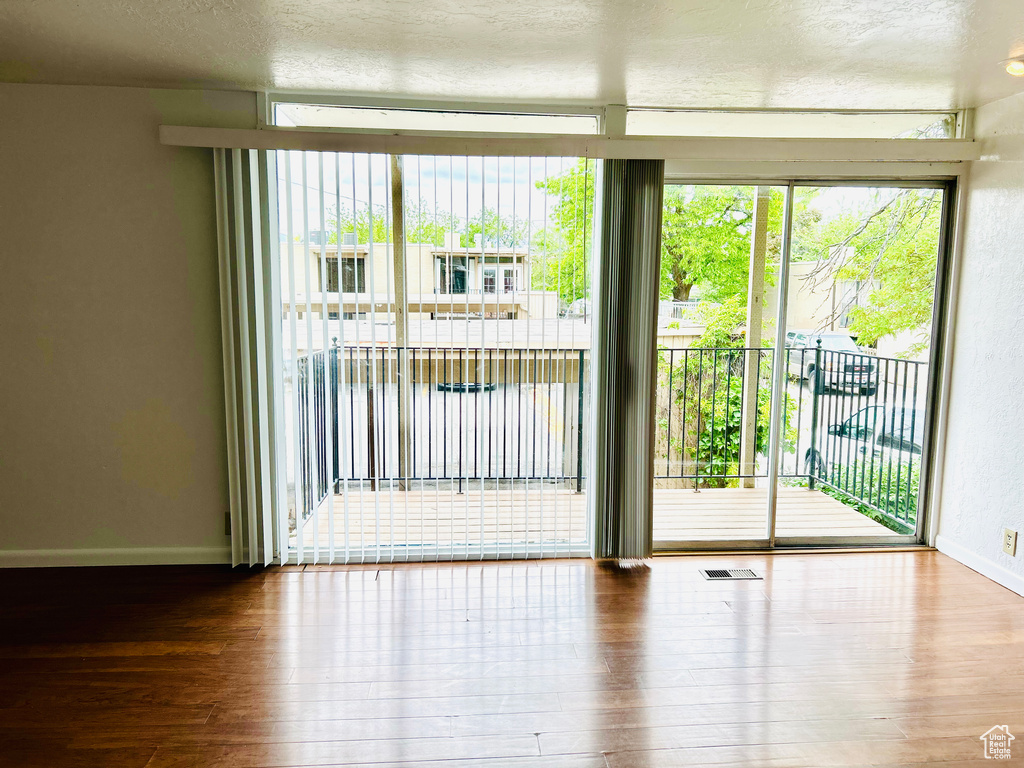 Empty room featuring hardwood / wood-style flooring, a textured ceiling, and baseboards