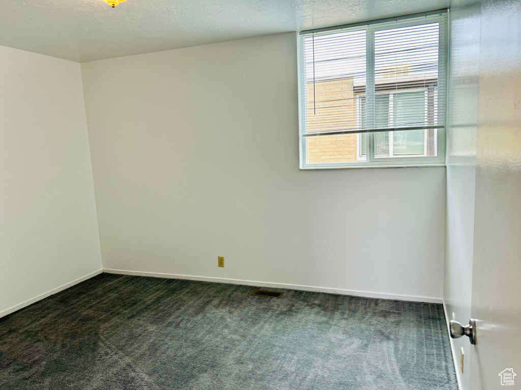 Unfurnished room with dark carpet and baseboards