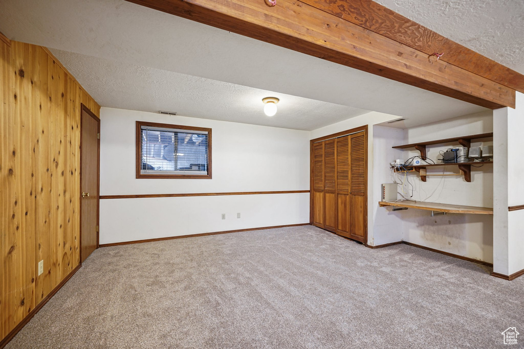 Finished below grade area with carpet, a textured ceiling, wooden walls, and baseboards
