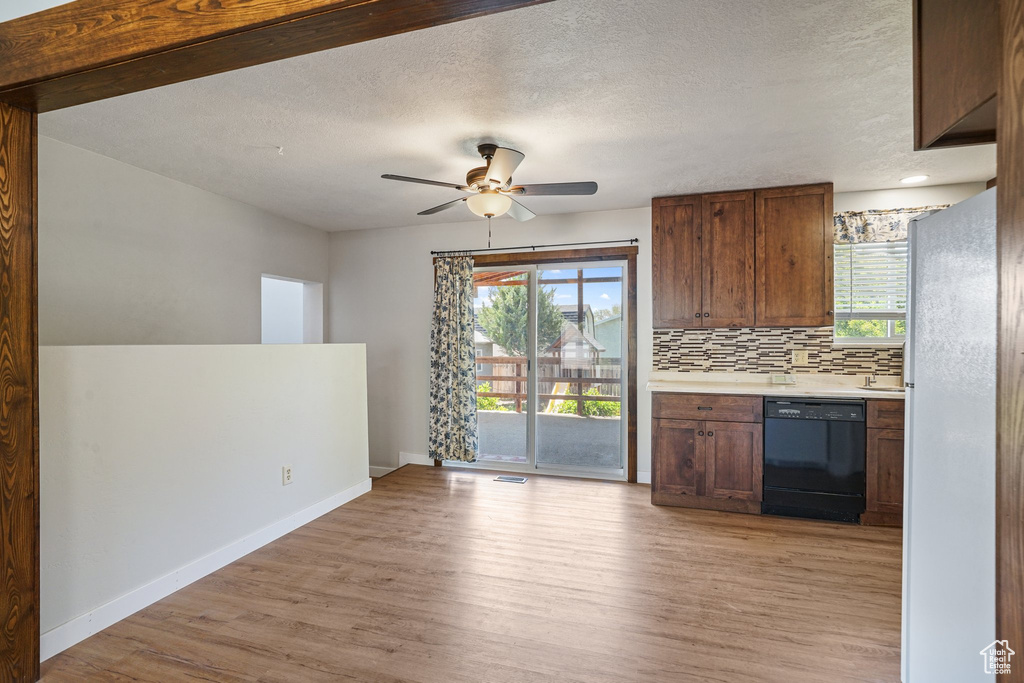 Kitchen with dishwasher, freestanding refrigerator, light wood-style floors, healthy amount of natural light, and a textured ceiling