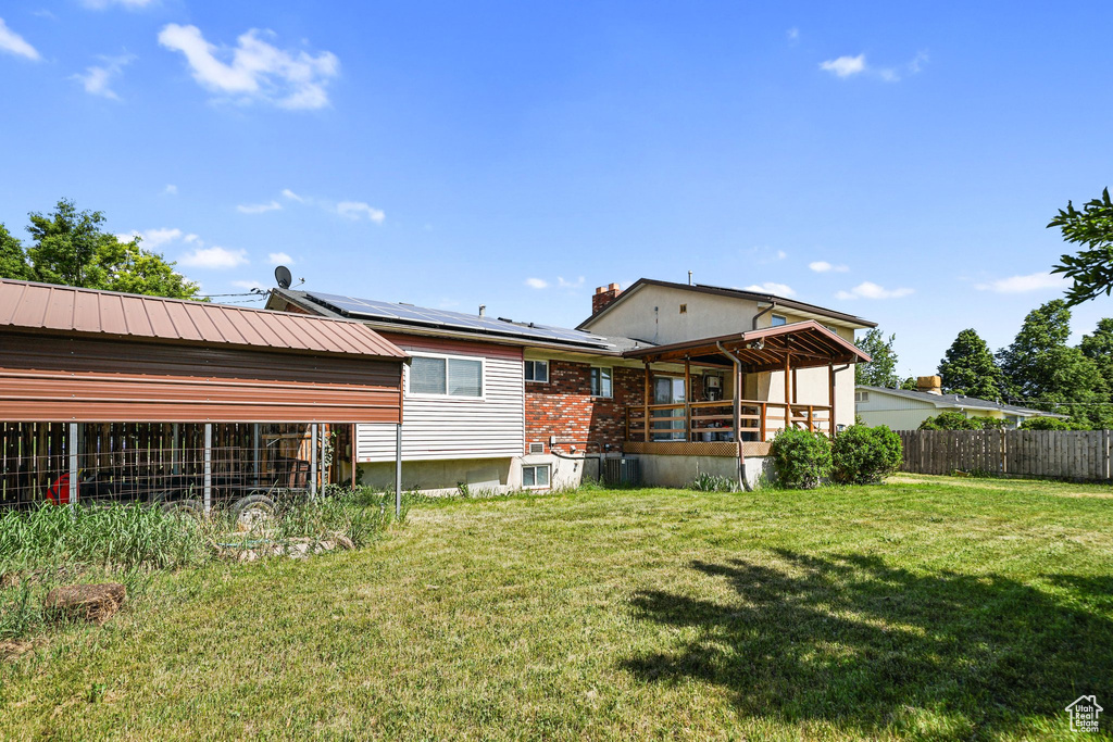 Rear view of house featuring roof mounted solar panels and a chimney