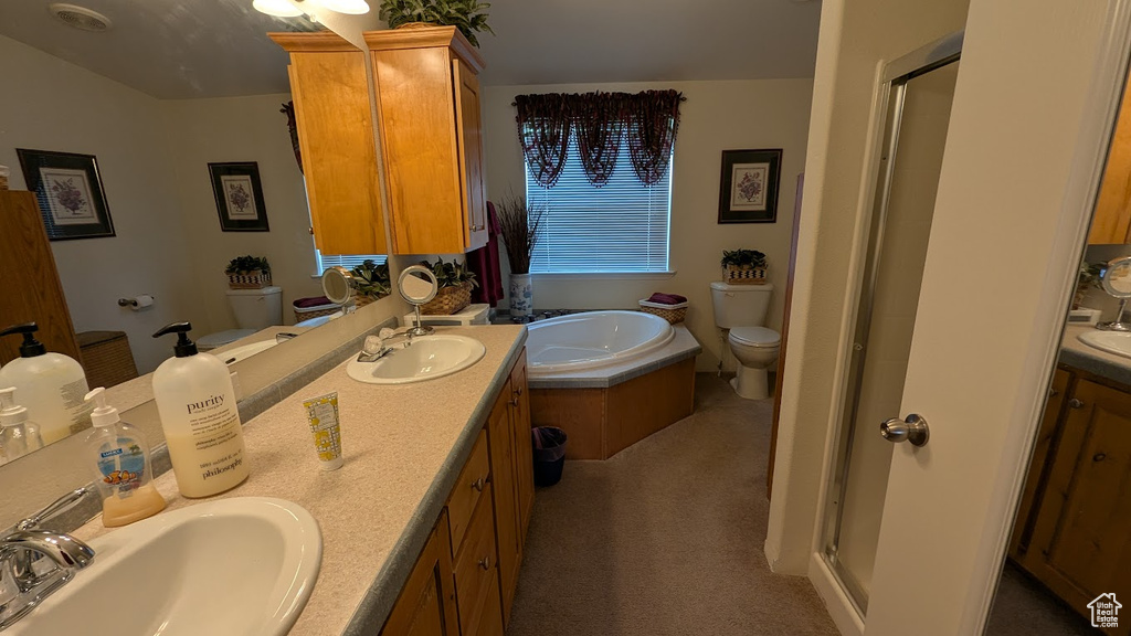Full bathroom featuring toilet, a stall shower, double vanity, and a bath
