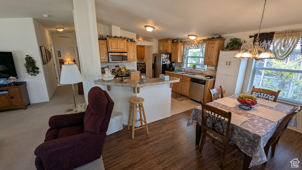 Kitchen featuring stainless steel appliances, a sink, a chandelier, a kitchen breakfast bar, and light countertops