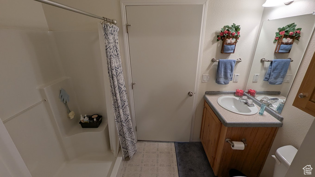 Bathroom with vanity, curtained shower, and toilet