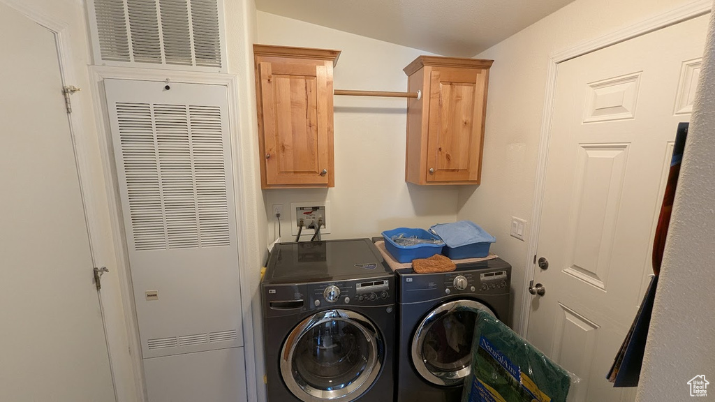 Laundry area featuring a heating unit, separate washer and dryer, and cabinet space