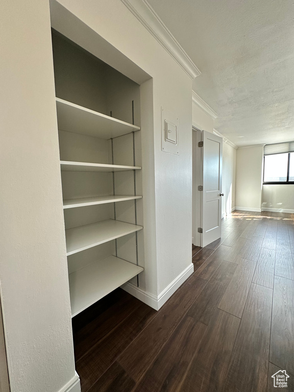 Hall featuring ornamental molding, wood finished floors, and a textured ceiling
