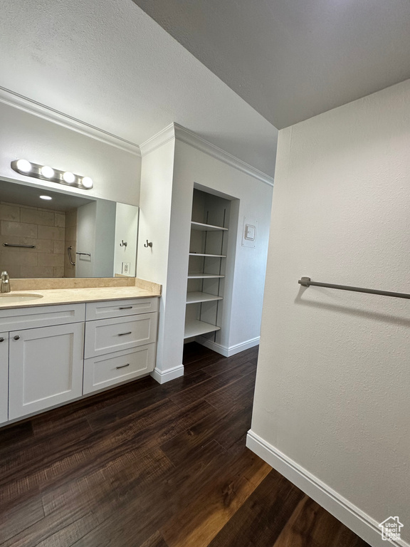 Bathroom with vanity, built in features, wood finished floors, crown molding, and a shower
