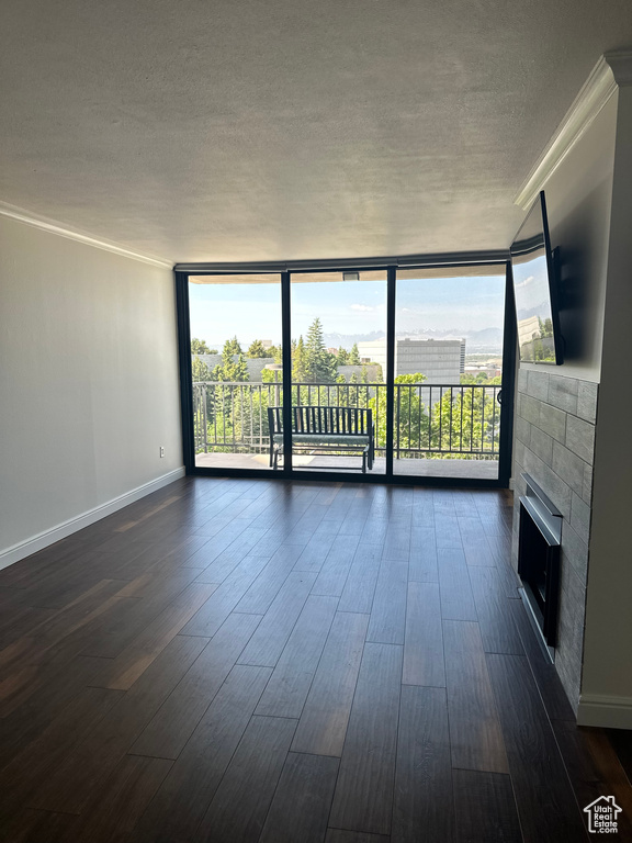 Unfurnished living room with expansive windows, plenty of natural light, a textured ceiling, dark wood finished floors, and a fireplace
