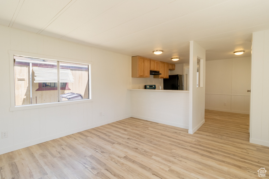 Unfurnished living room with light wood-style floors and baseboards