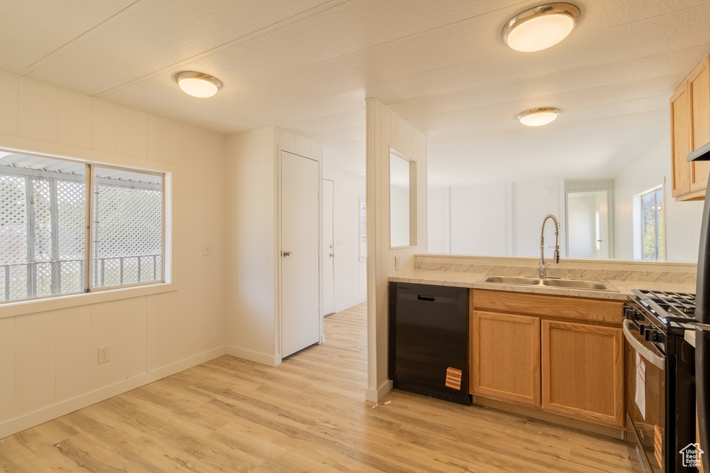 Kitchen featuring black dishwasher, a sink, gas stove, and light wood-style flooring