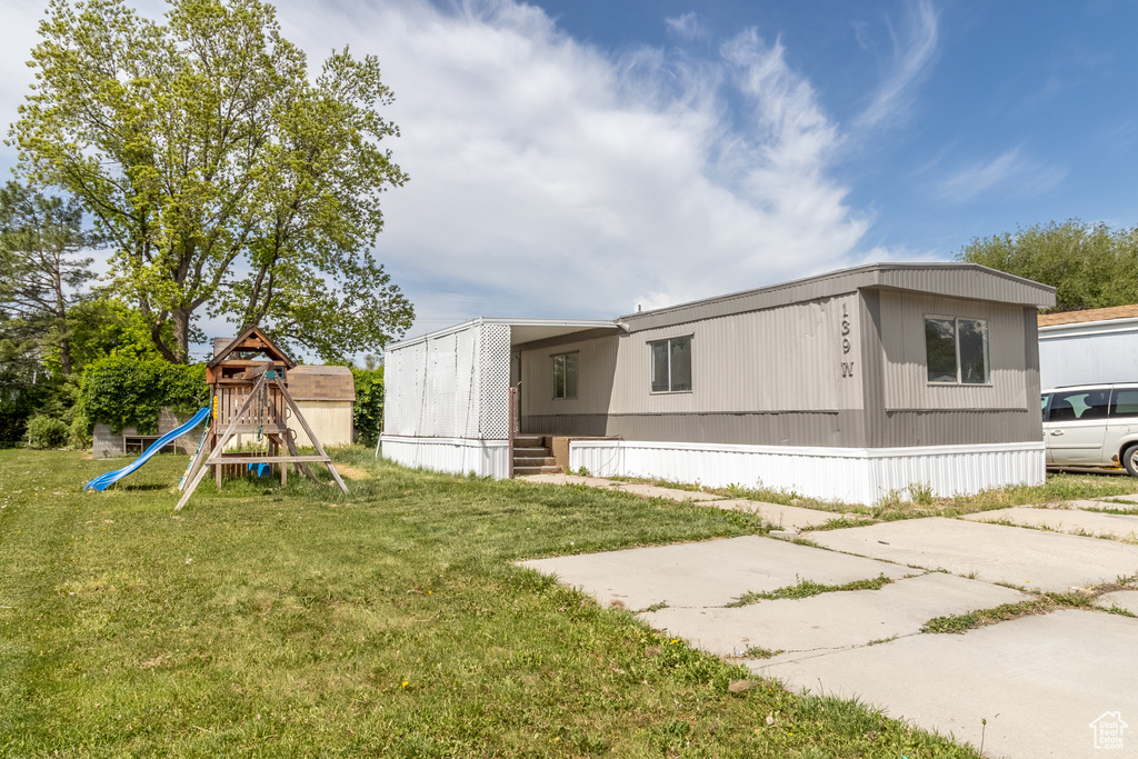 Back of house with a playground and a yard