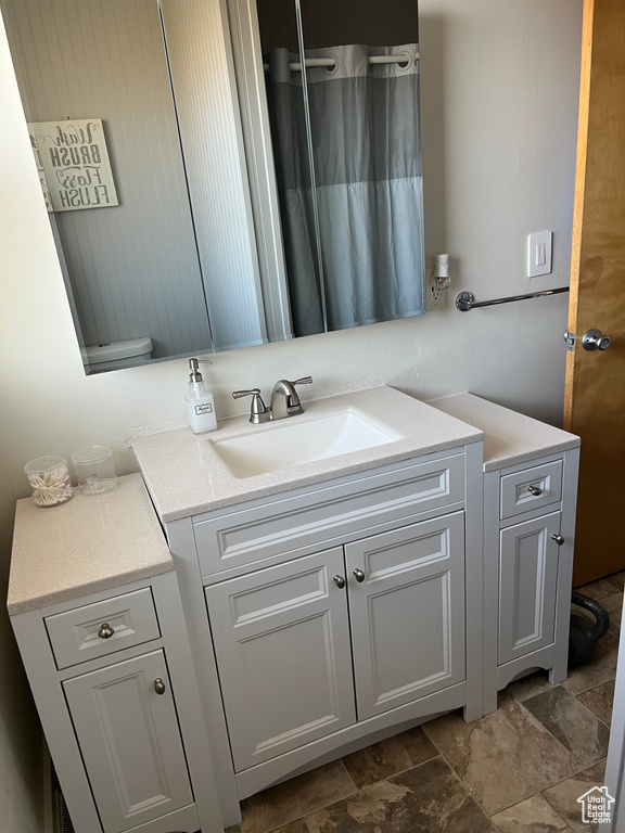 Full bath featuring vanity, stone finish flooring, and curtained shower