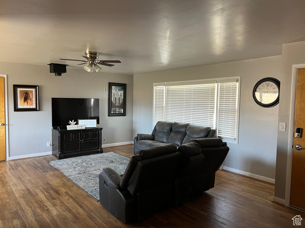 Living area featuring a ceiling fan, dark wood finished floors, and baseboards