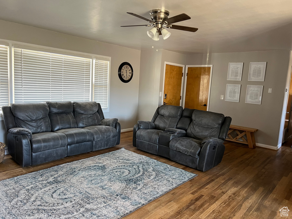 Living area featuring a ceiling fan, wood finished floors, and baseboards