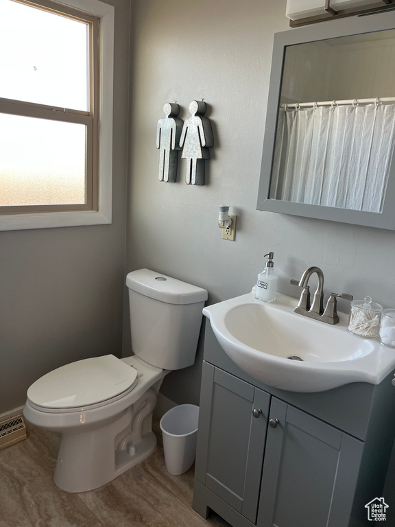 Full bath featuring vanity, toilet, and baseboards