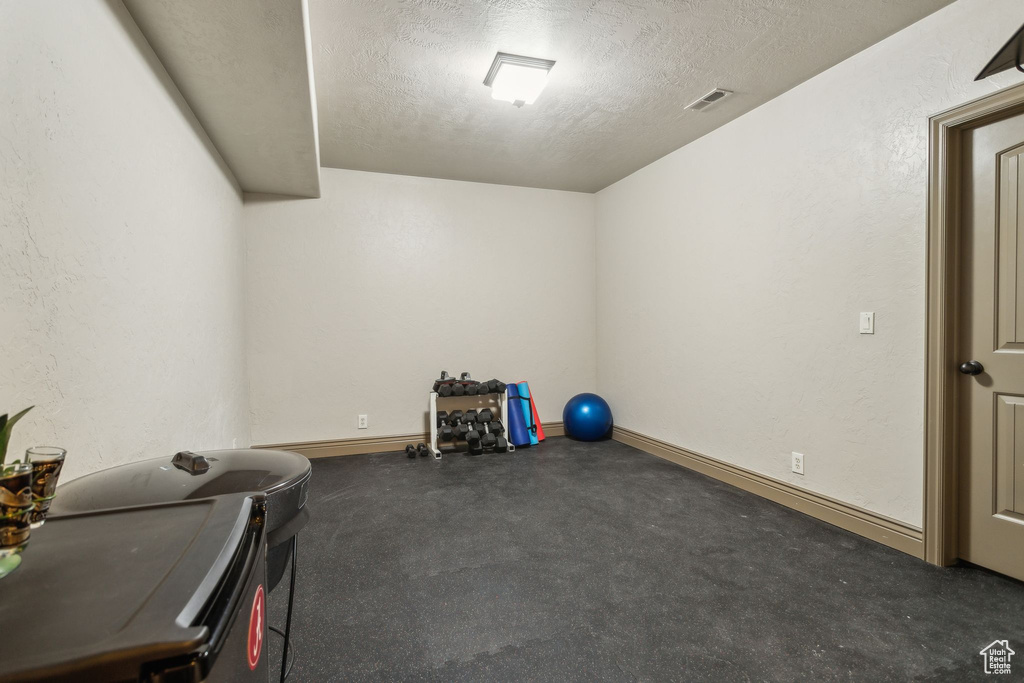 Workout room featuring a textured ceiling and baseboards
