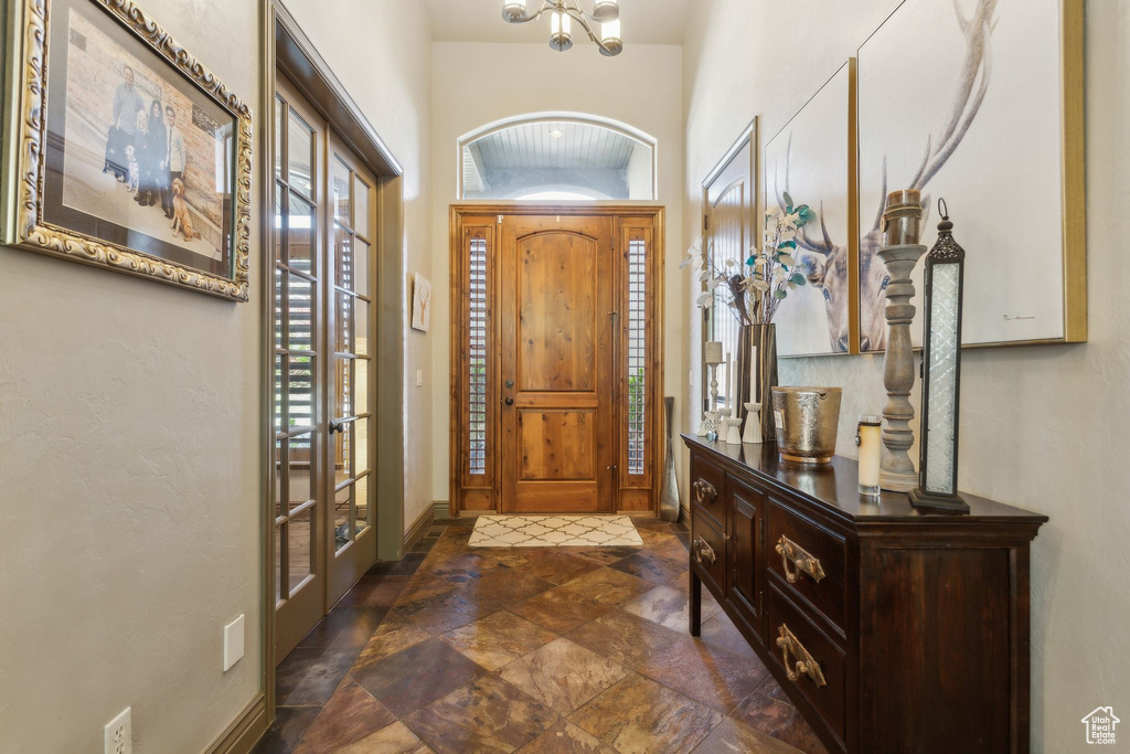 Entryway with a chandelier, dark stone finish flooring, french doors, and baseboards