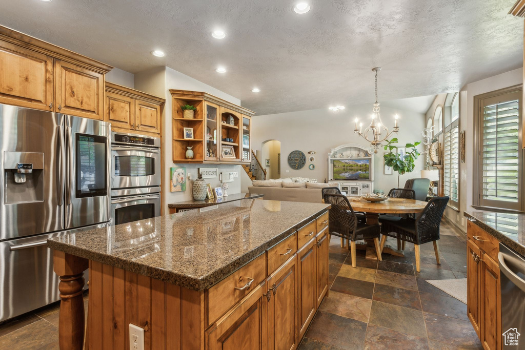 Kitchen with stainless steel appliances, brown cabinetry, open shelves, a center island, and recessed lighting
