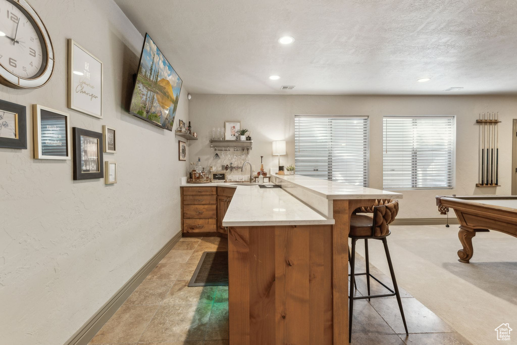 Kitchen with a kitchen breakfast bar, a peninsula, light countertops, baseboards, and recessed lighting
