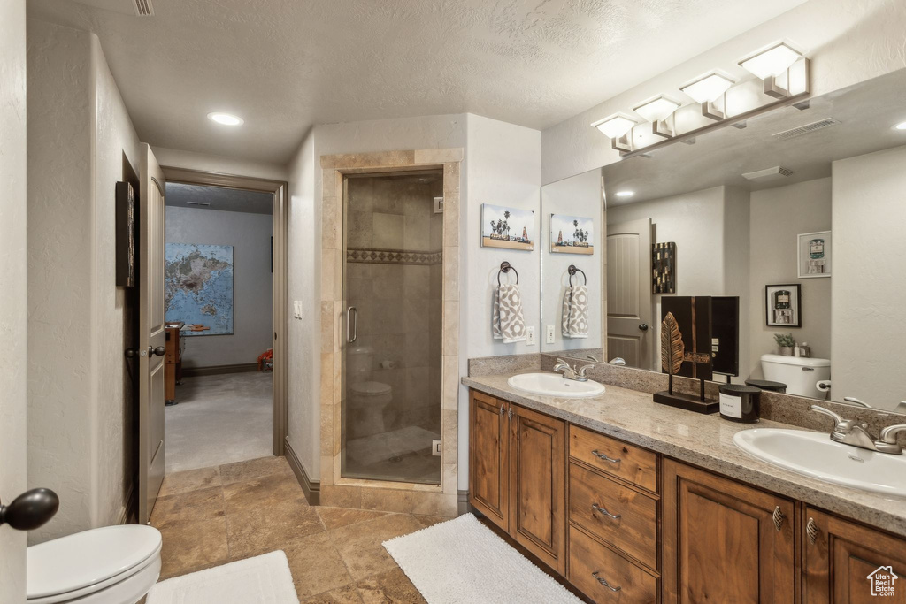 Bathroom with toilet, a stall shower, double vanity, and recessed lighting