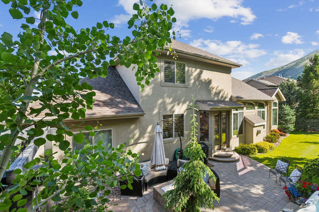 View of front of home with stucco siding, roof with shingles, and a patio area