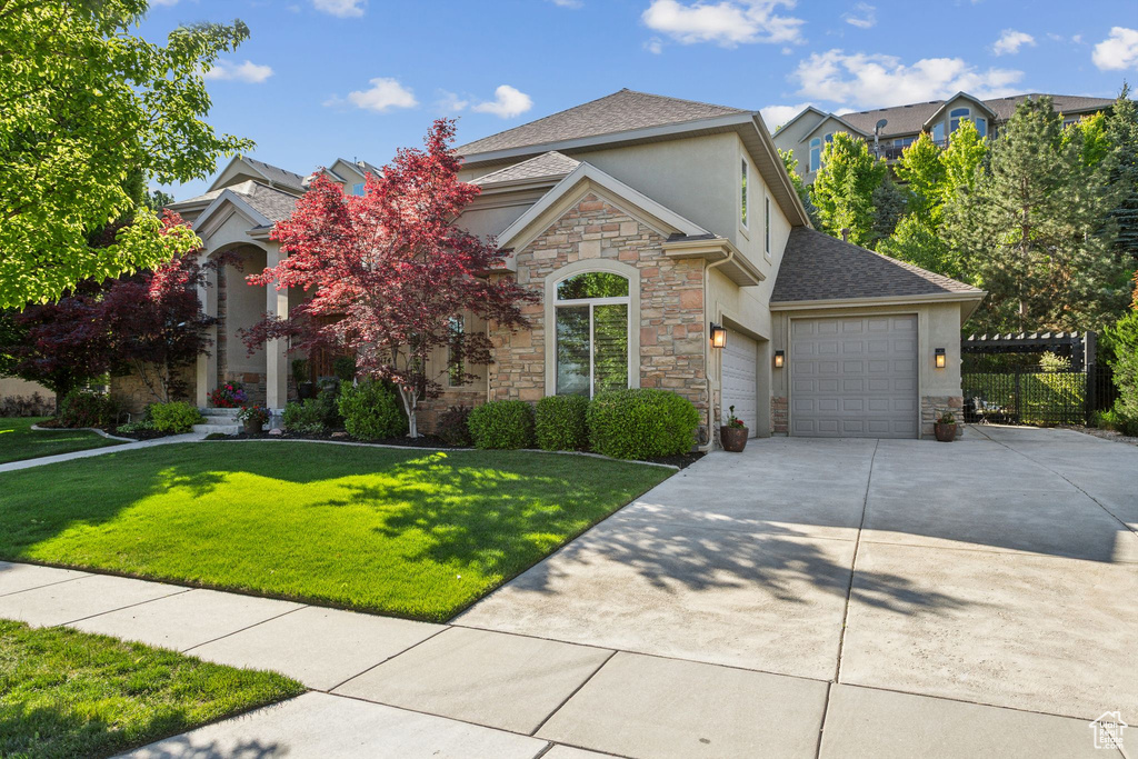 View of front facade featuring stone siding, stucco siding, concrete driveway, and a garage