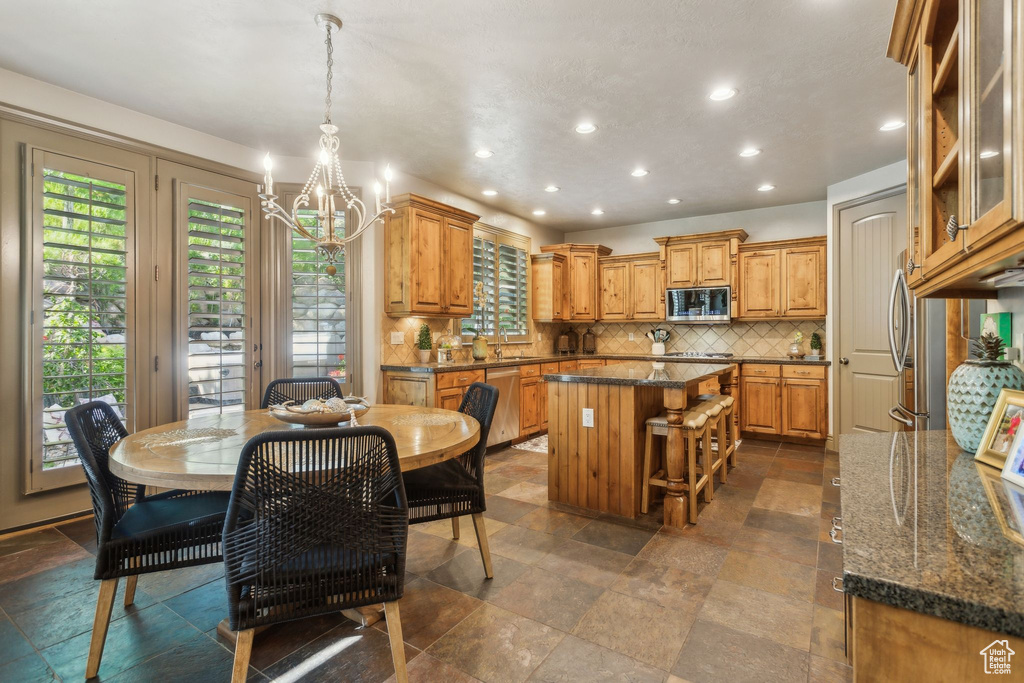 Dining space with a chandelier, recessed lighting, and dark stone finish flooring