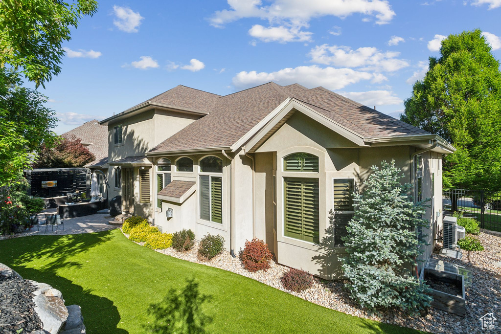 Back of house featuring stucco siding, a shingled roof, and a patio