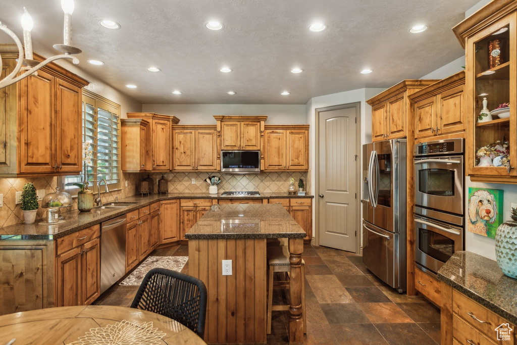 Kitchen with appliances with stainless steel finishes, a sink, recessed lighting, and brown cabinets