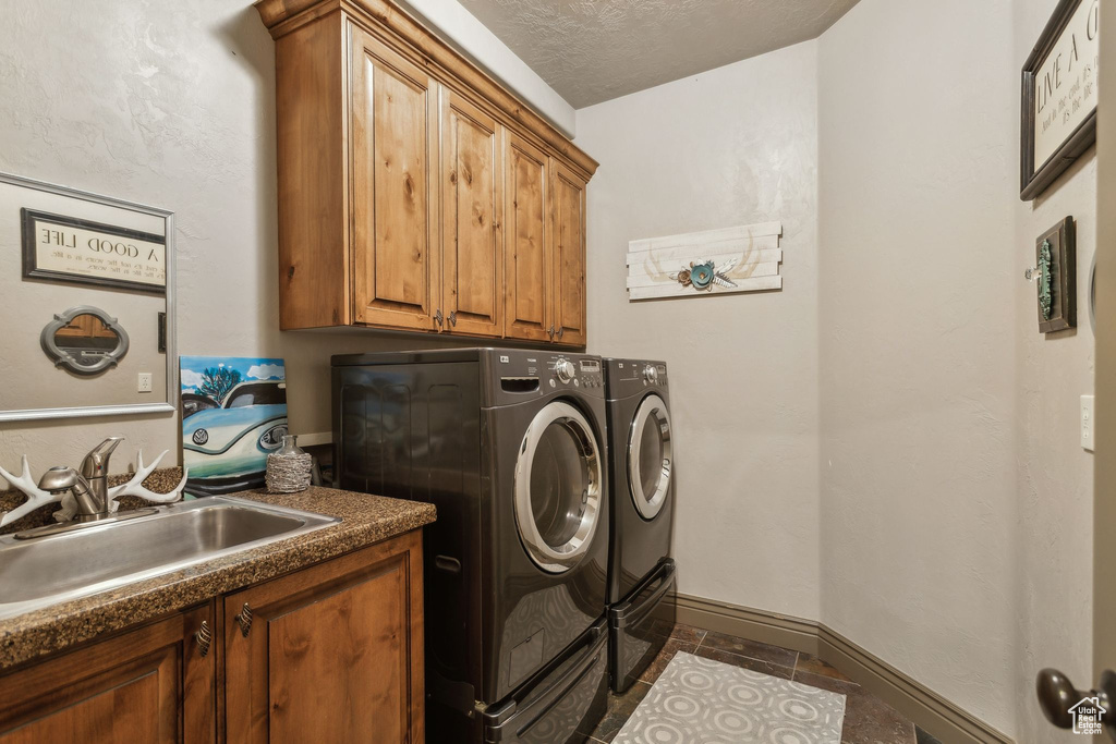 Laundry room featuring washing machine and dryer, cabinet space, baseboards, and dark tile patterned floors