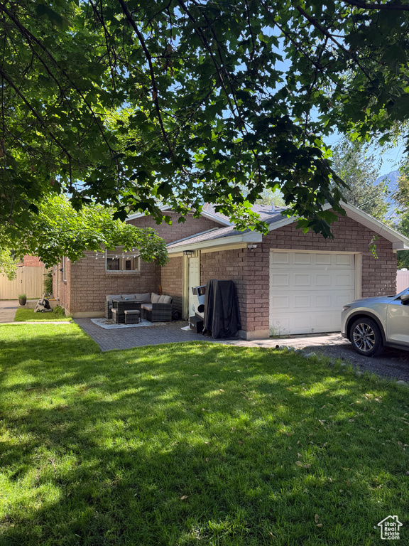View of green lawn with outdoor lounge area and a garage