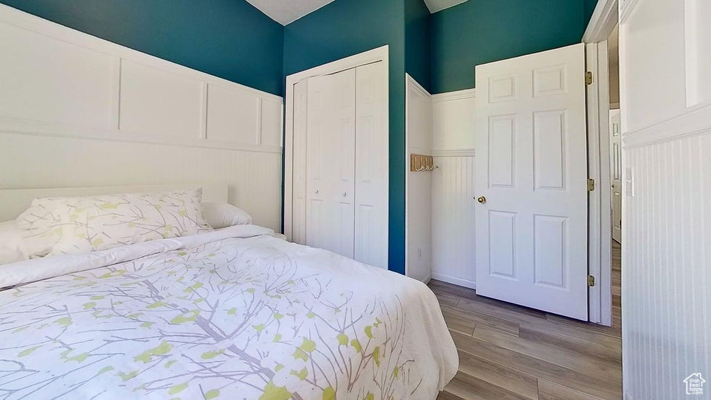 Bedroom with wood finished floors and a closet