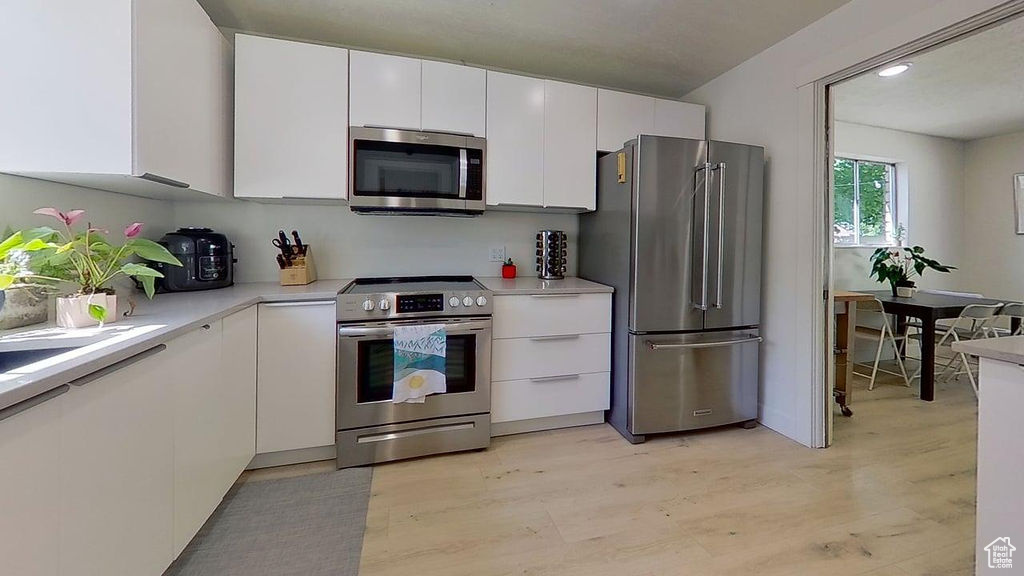 Kitchen featuring appliances with stainless steel finishes, white cabinets, and light countertops