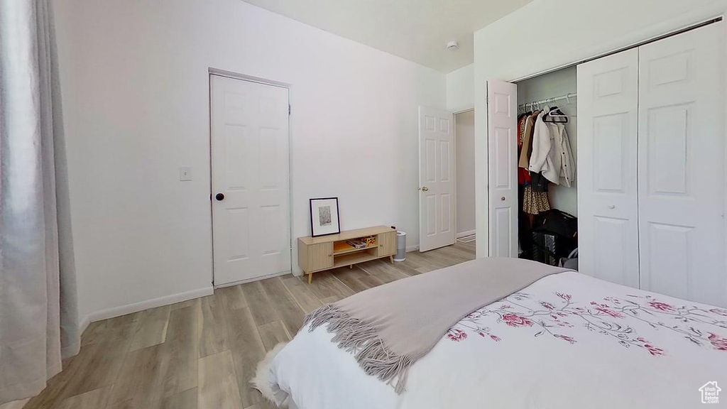 Bedroom with light wood-style flooring, baseboards, and a closet