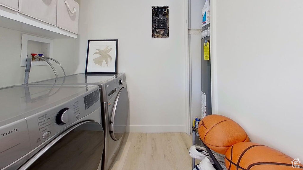 Washroom with cabinet space, separate washer and dryer, light wood-style flooring, and baseboards