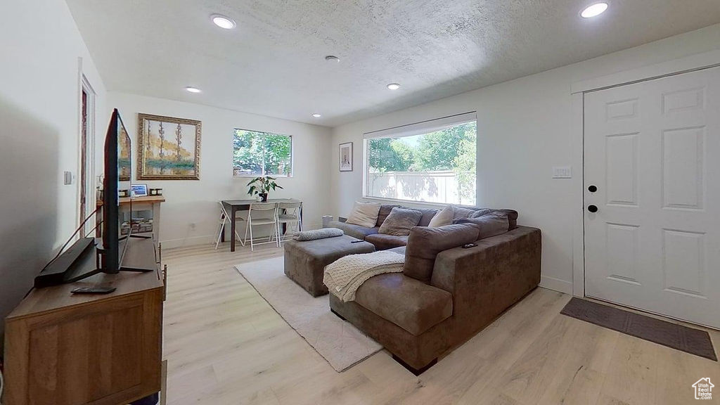 Living room featuring light wood finished floors, recessed lighting, baseboards, and a textured ceiling