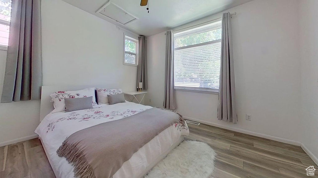 Bedroom featuring wood finished floors, baseboards, attic access, and a ceiling fan