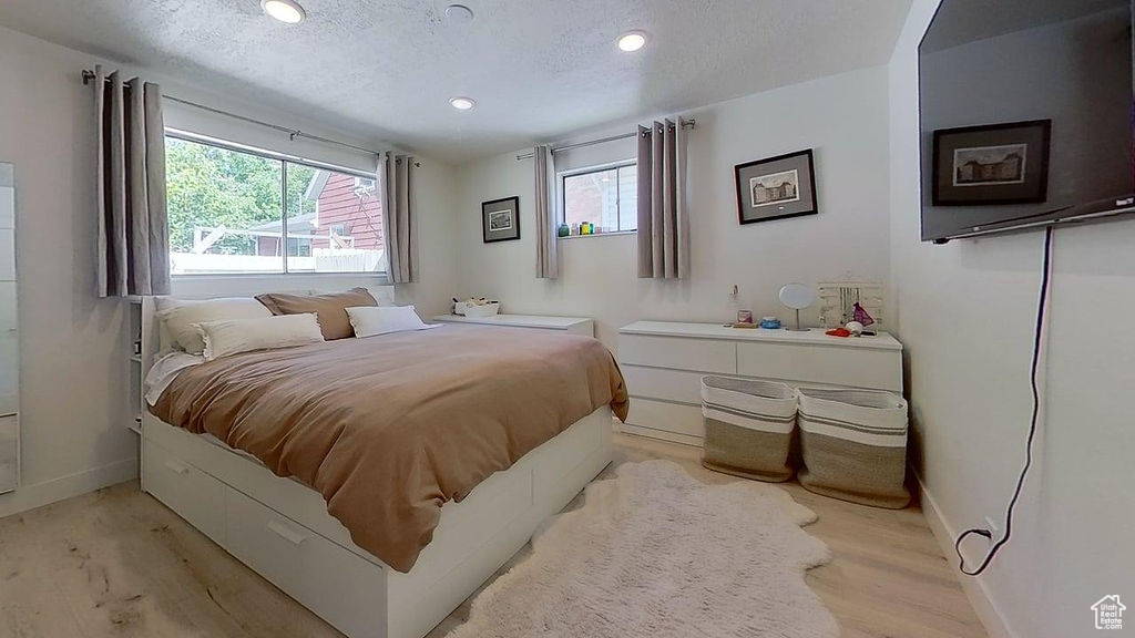 Bedroom featuring multiple windows, baseboards, light wood-style floors, a textured ceiling, and recessed lighting
