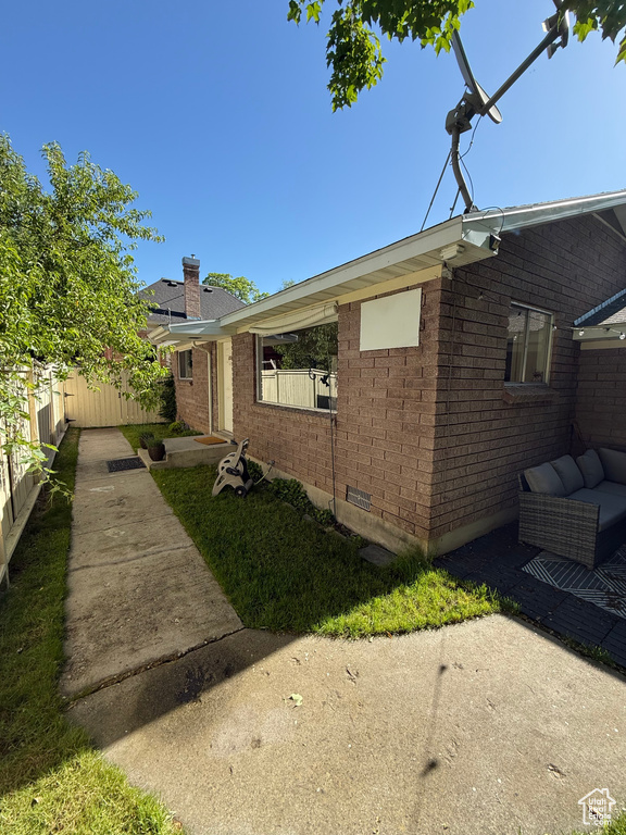View of front of house featuring a chimney, brick siding, and a patio area