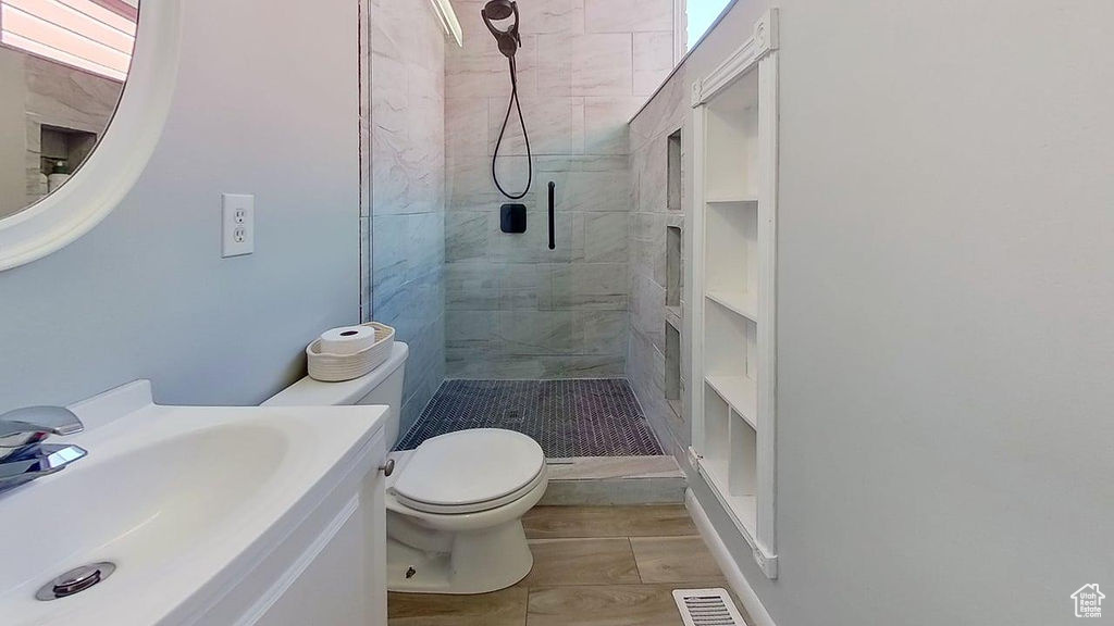 Bathroom featuring tiled shower, toilet, and vanity